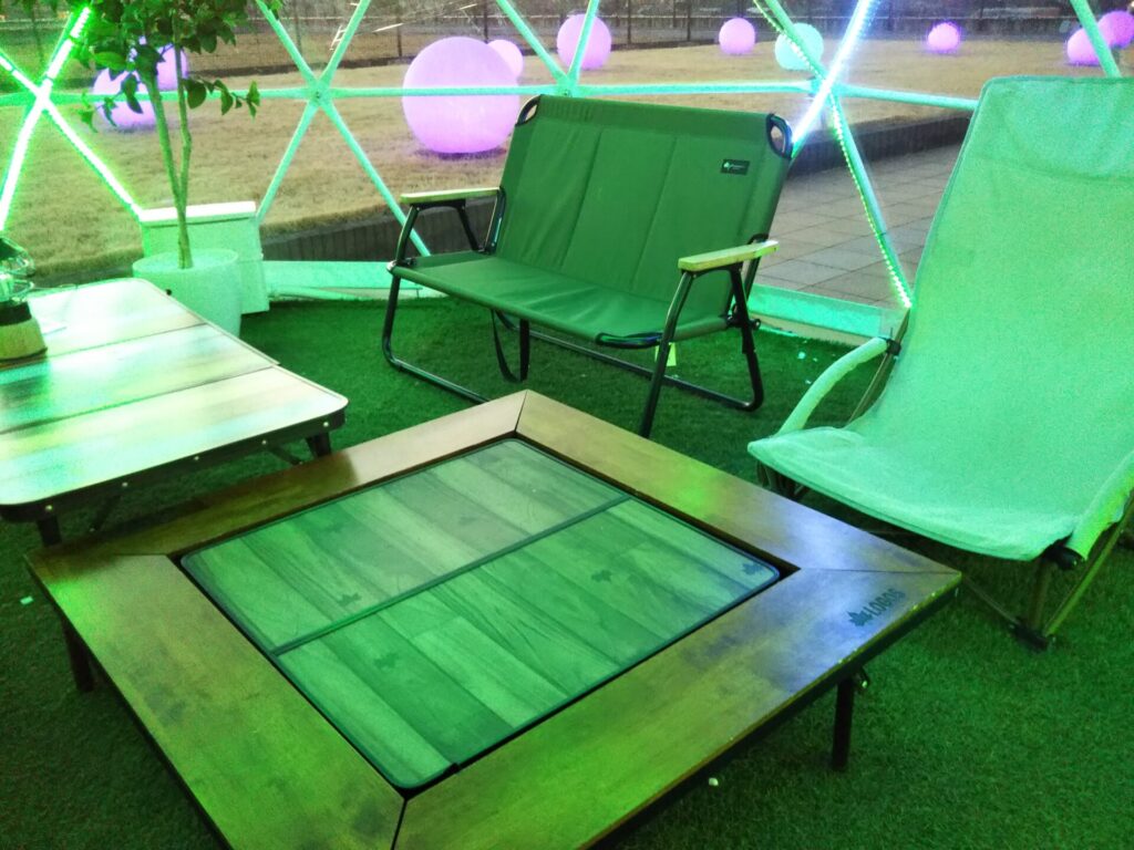 透明ドームの中に設けられたテーブルとチェアのある全天候型テラス。天候を気にせず屋外空間を楽しめるくつろぎスペース
