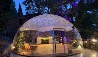夜間にライトアップされた透明ガラスドーム「AURA DOME」の外観。ホテルやリゾート施設のラウンジ・イベントスペースとして活用できる全天候型ドーム建築。